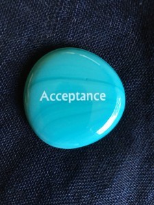 A small blue stone with the word "Acceptance" engraved on it.