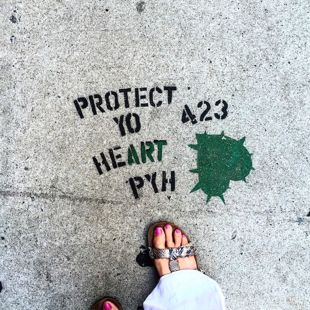 A stenciled message on a sidwalk: "PROTECT YO HEART PYH 423"