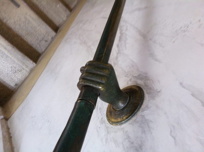 A decorative metal hand holding a metal rod.