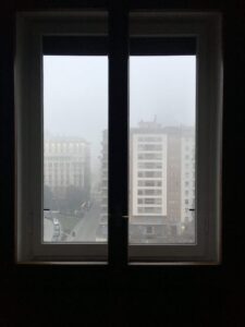 Looking through a window at a foggy cityscape.