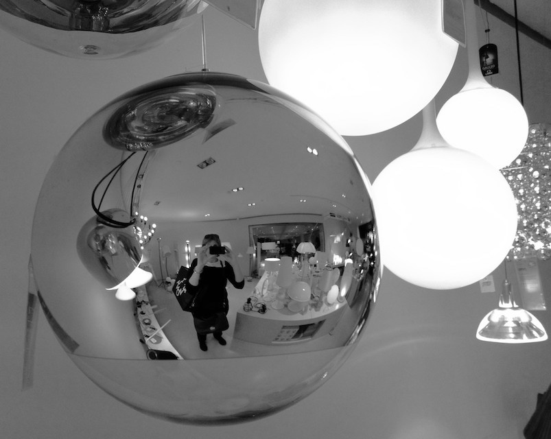 A shiny round ball showing a reflection of Melinda taking a photo of the ball.